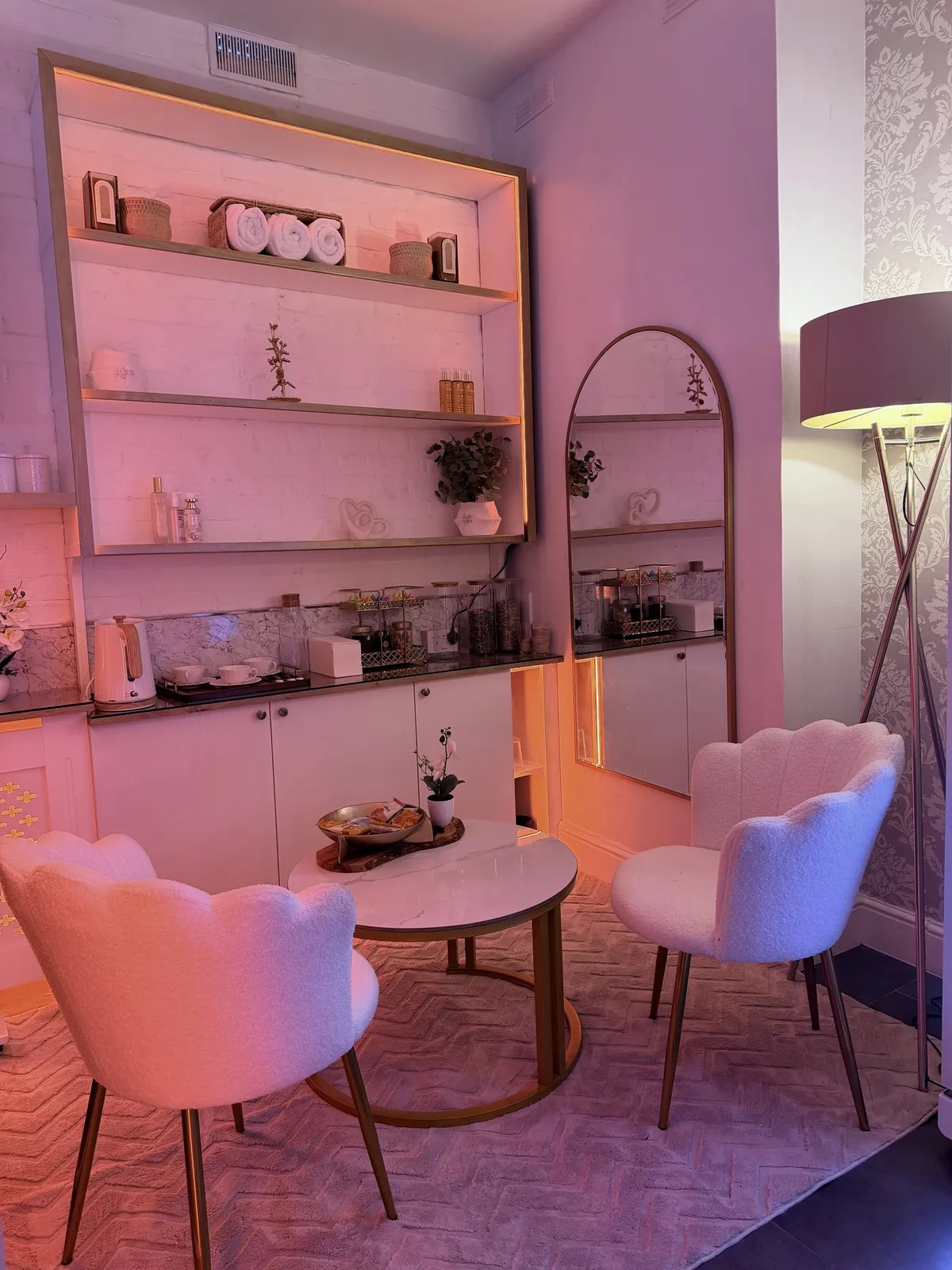 The Vora Wellness reception area with two chairs, a round table and warm studio lighting